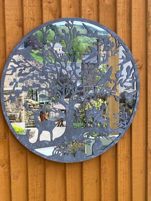 Une œuvre d’art circulaire en métal, représentant un arbre, fixée sur une clôture en bois.