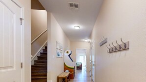 A hallway with a wooden staircase, a bench, and a wall-mounted rack. - Shared Heated Pool With Slide, Golf Cart Accessible, Pet Friendly (Port Aransas)