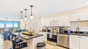 A modern kitchen with white cabinets, stainless steel appliances, and a large island with bar stools.