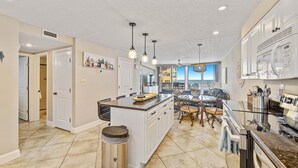 A modern kitchen with a central island, pendant lighting, and a view to the outside.