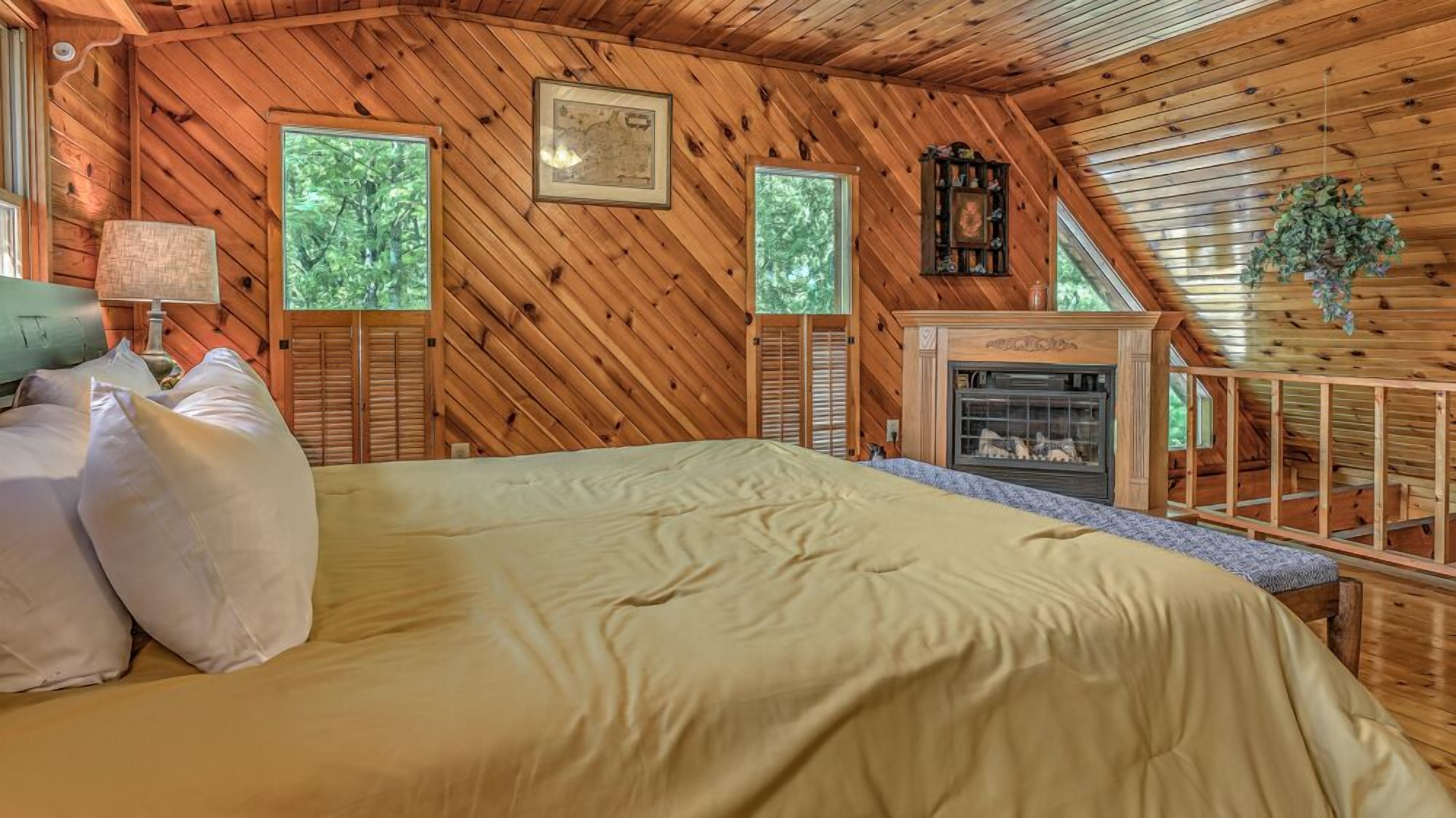 Camera da letto in una baita di legno, con un letto, un camino e due finestre.