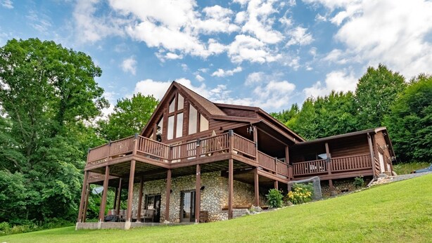 A large wooden cabin with a stone foundation, multiple balconies, and a grassy landscape. - Panoramic Point - 91 Panoramic Drive (Dryfork)