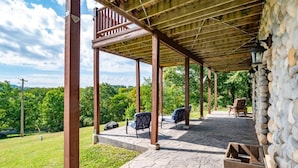 A covered outdoor area with stone flooring, wooden pillars, and a stone wall.