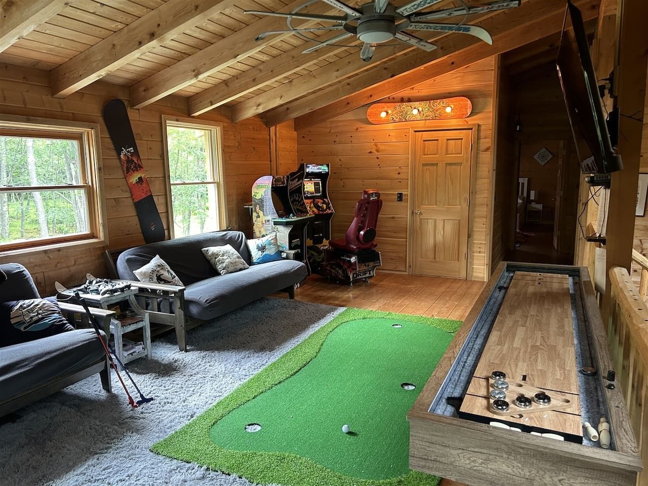 A cozy room with a shuffleboard table, a sofa, and a gaming table.