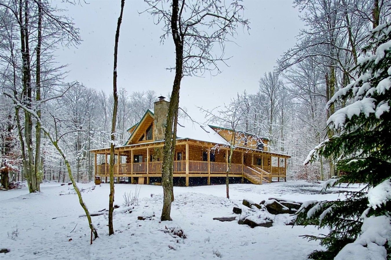 Uma cabana de madeira com varanda, rodeada por árvores cobertas de neve.