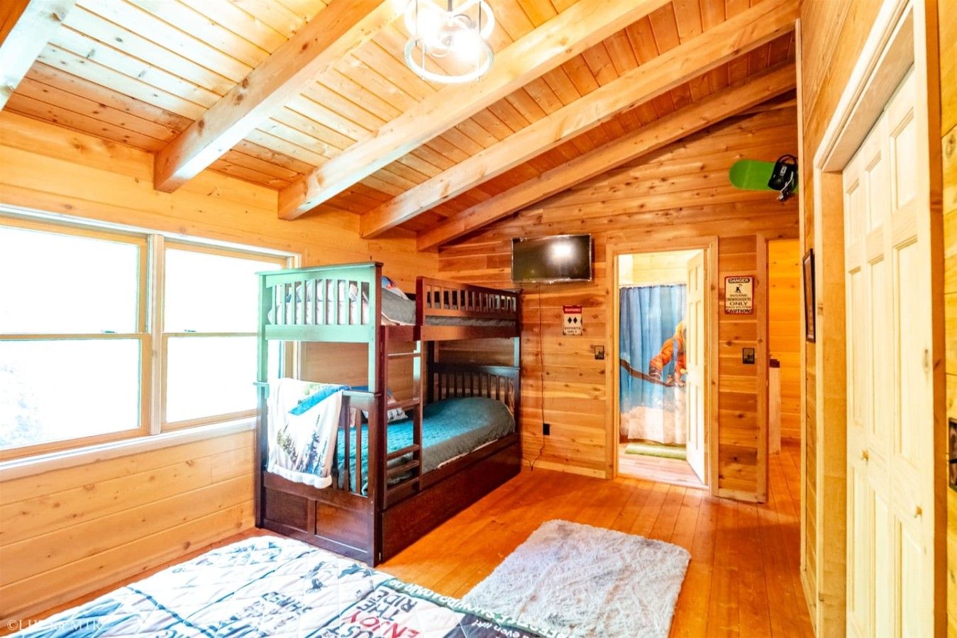 A wooden cabin with bunk beds, a television, and a caution sign.