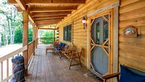 A wooden cabin with a porch, wooden benches, and a welcome sign. - Countless Adventures (Davis)