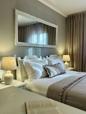 A hotel room with a large bed, two bedside lamps, a mirror above the bed, and a window with curtains. - Villa Silente (Oklaj)