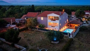 A two-story house with a swimming pool, surrounded by greenery and a view of distant mountains. - Villa Silente (Oklaj)
