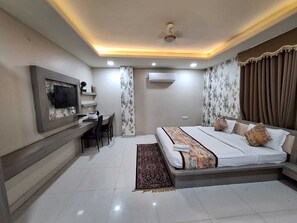 A modern bedroom with a bed, bedside tables, a desk, and a television.