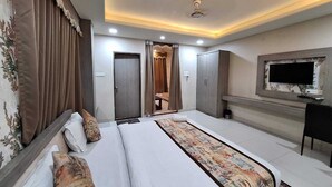 A hotel room with a large bed, a television, and a wardrobe. - Hotel Mayur Palace (Bhopal)