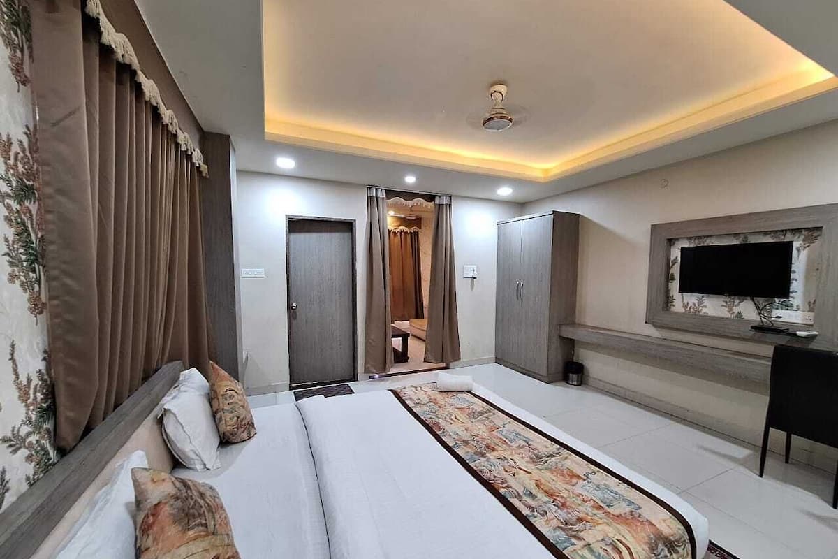 A hotel room with a large bed, a television, and a wardrobe.