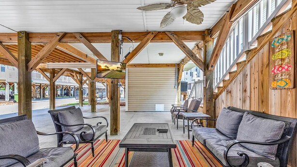 An outdoor patio with wooden beams, a ceiling fan, and a view of the street. - Vacation home in Ocean lakes at Myrtle beach (Myrtle Beach)