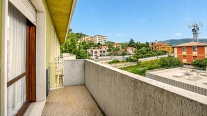 Een balkon met een versierde vloer, uitzicht op gebouwen en een heldere lucht.