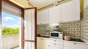 Een keuken met een schuifdeur naar een balkon, een magnetron, een fornuis en een spoelbak.