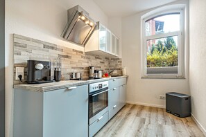 A modern kitchen with a built-in oven, a coffee maker, and a window with a view of trees.