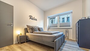 Un dormitorio con una cama, una mesita de noche con lámpara, una ventana con vistas y un armario.