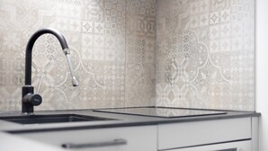 A kitchen with a modern faucet, a built-in oven, and patterned backsplash tiles. - Studio Apartment: Loft with Lake View (Petersthal)