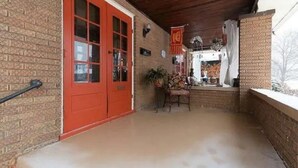 Un espace extérieur abrité, doté d’un mur en briques, d’une porte rouge et d’une table avec des chaises.