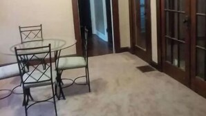 Une pièce dont le sol est recouvert d’une moquette, avec une table ronde entourée de chaises et une porte dotée de panneaux de verre.