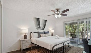 Relax in this serene bedroom with a large bed, bedside tables, and a ceiling fan. Enjoy the view from the large window.