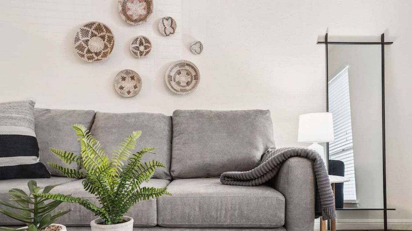 A modern living room with a grey sofa, a glass coffee table, and decorative wall art.
