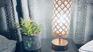 A bedside table with a potted plant and a decorative lamp. - Luxury 2 bedroom 🛌 Next to UBS Arena🏟 & JFK✈️ (Valley Stream)