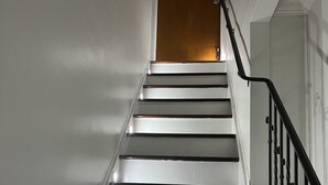 A staircase with white walls and a wooden door at the top. - Luxury 2 bedroom 🛌 Next to UBS Arena🏟 & JFK✈️ (Valley Stream)