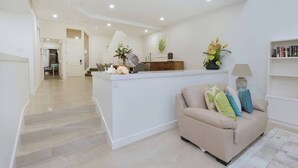 Een modern interieur met een centraal eiland, een bank en een trap naar een andere kamer.