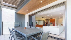 An outdoor dining area with a table and chairs, a wooden ceiling, and a view into the house. - Villa On The Hill —Spacious Tropical Panorama (Port Douglas)