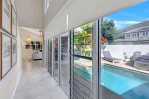 Un'area piscina interna moderna con porte in vetro, una poltrona e un divano.