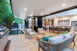 Una cocina moderna con comedor, piscina y escalera que sube a un nivel superior.