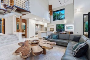 Un amplio salón con una escalera moderna, una gran mesa de comedor y un sofá confortable.