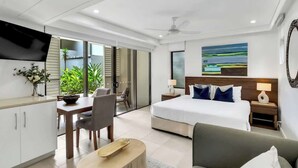 Una habitación de hotel moderna con cama, sofá, zona de comedor y televisor.