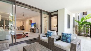 Una sala de estar moderna con puerta de vidrio que da a un balcón, un conjunto de sofá y un televisor.