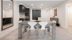 Una cocina moderna con comedor que incluye una mesa de madera y sillas blancas.