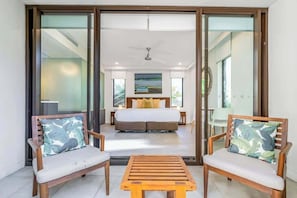 A bedroom with a bed, two wooden chairs with cushions, a small wooden table, and a ceiling fan. - Resort-style Swim Out: A Poolside Oasis (Port Douglas)