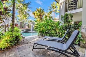 A poolside area with lounge chairs, a small pool, and tropical plants.