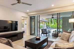 A modern living room with a flat-screen TV, dark coffee table, and a sofa.