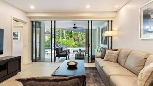 A modern living room with a sofa, coffee table, and TV. - The Plunge Pool Residence—Private Resort Living (Port Douglas)