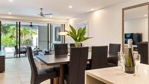 A modern dining area with a large table, chairs, and a decorative plant. - The Plunge Pool Residence—Private Resort Living (Port Douglas)
