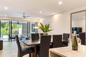 Un'area pranzo moderna con un tavolo grande, sedie e una pianta decorativa.