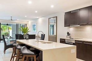Een moderne keuken met een centraal eiland, donkere kastjes en een groot raam.