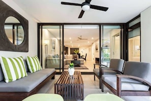 Un soggiorno moderno con divano, poltrone, tavolino e ventilatore a soffitto.