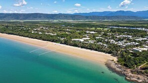 Vista aerea di una zona costiera con spiaggia, campo da golf e area residenziale con case.