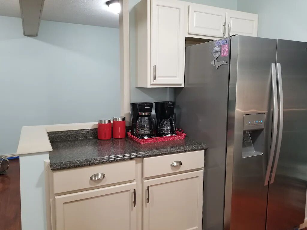 A kitchen with a stainless steel refrigerator, a countertop with a coffee maker, and a red mug.