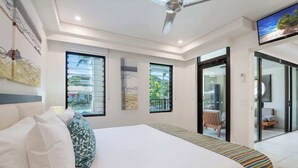 A modern hotel room with a large bed, a ceiling fan, and a TV mounted on the wall. - Swim-out Tropical Getaway by Four Mile Beach (Port Douglas)