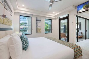 A modern hotel room with a large bed, a ceiling fan, and a TV mounted on the wall. - Swim-out Tropical Getaway by Four Mile Beach (Port Douglas)