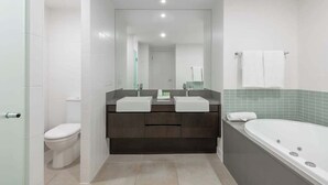 A modern bathroom with a dual sink vanity, a toilet, and a bathtub. - Swim-out Tropical Getaway by Four Mile Beach (Port Douglas)