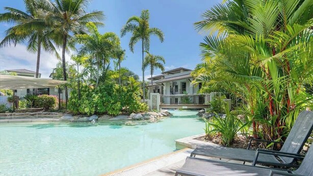 A pool with lounge chairs, surrounded by palm trees and a building with a balcony. - Swim-out Tropical Getaway by Four Mile Beach (Port Douglas)